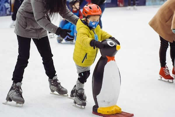 un niño con su madre aprendiendo a patinar sobre hielo